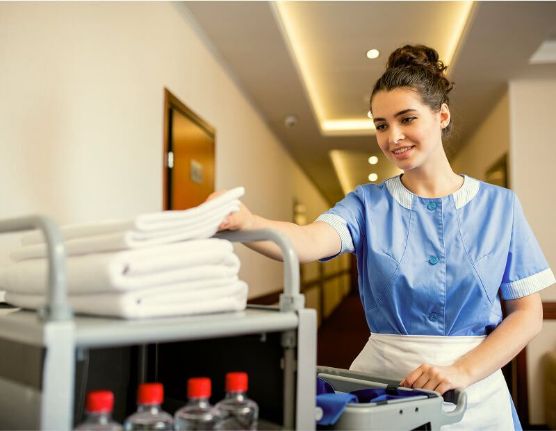 frau-hotelmitarbeiter Fröhliche Frau, die ein Handtuch in der Hand hält